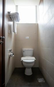 a bathroom with a white toilet and a window at Swiss Hotel Apartment in Kuala Belait