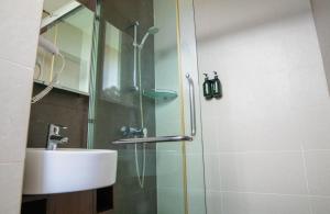 a bathroom with a shower with a sink and a glass shower door at Swiss Hotel Apartment in Kuala Belait