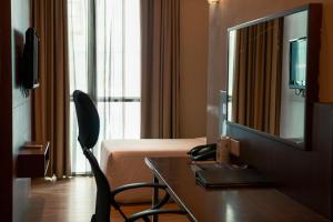 a hotel room with a bed and a table and a television at Swiss Hotel Apartment in Kuala Belait