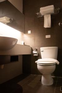 a bathroom with a toilet and a sink and towels at Swiss Hotel Apartment in Kuala Belait