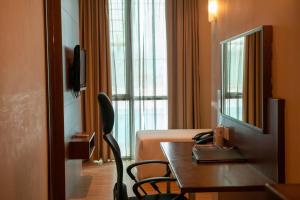a hotel room with a bed and a table and a mirror at Swiss Hotel Apartment in Kuala Belait
