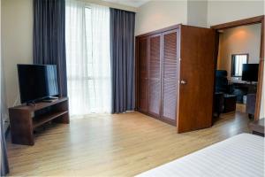 a hotel room with a bed and a television at Swiss Hotel Apartment in Kuala Belait