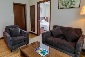 a living room with a couch and two chairs and a table at Swiss Hotel Apartment in Kuala Belait