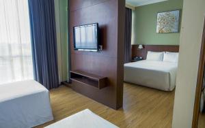 a hotel room with two beds and a tv at Swiss Hotel Apartment in Kuala Belait