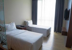 a hotel room with two beds and a window at Swiss Hotel Apartment in Kuala Belait