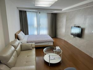 a living room with a couch and a bed at Haeundae Beach Stay Hotel in Busan