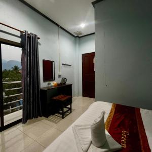 a bedroom with a bed and a desk and a television at VangVieng Smile guesthouse in Vang Vieng