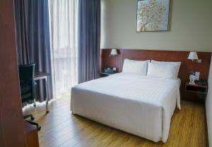 a hotel room with a large bed and a television at Swiss Hotel Apartment in Kuala Belait