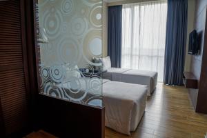a hotel room with two beds and a window at Swiss Hotel Apartment in Kuala Belait