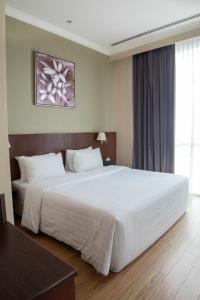 a bedroom with a large white bed in a room at Swiss Hotel Apartment in Kuala Belait