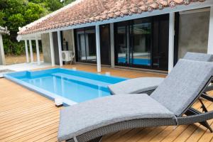 a deck with two chairs and a swimming pool at Tida Sesoko in Motobu