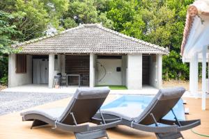 a gazebo with two chairs and a swimming pool at Tida Sesoko in Motobu