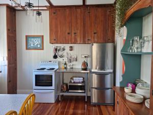 a kitchen with white appliances and wooden cabinets at Waitawheta Cottage in Waihi