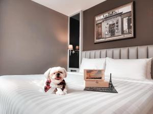 a dog wearing a bow tie sitting on a bed at Quartier by Montraj Sukhumvit Bangkok in Bangkok