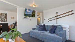 a living room with a blue couch and a table at Lawlers 30 in Mount Hotham