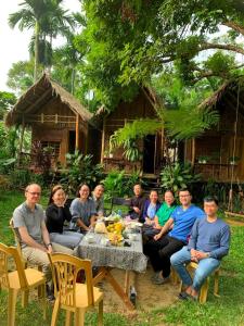 a group of people sitting around a table in front of a house at NaCo Lodge Homestay in Pu Luong
