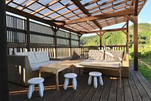 a wooden deck with a wooden pergola and a table and chairs at 古民家ゲストハウスSatoyama in Kokuryō