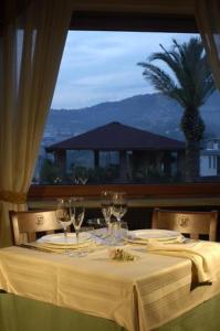uma mesa com copos de vinho e vista para uma palmeira em Hotel Lemi em Benevento