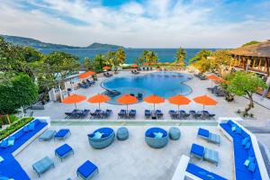 an aerial view of a resort pool with orange umbrellas at Diamond Cliff Resort & Spa, Patong Beach in Patong Beach