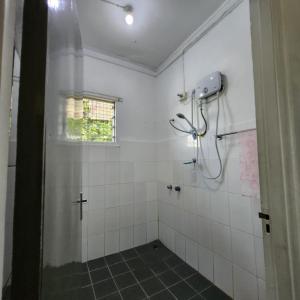a bathroom with a shower with white tiles at Wane's BnB in Nadi