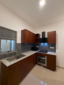 a kitchen with wooden cabinets and a sink and a window at Elixia 3C'S by Planet Path in Sri Jayewardenepura Kotte