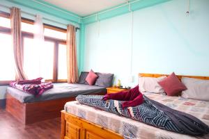two beds in a room with blue walls and windows at Okhli Homestay in Kalimpong