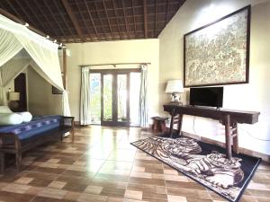 a room with a bed and a table and a television at Villa Plawa Asri in Seminyak