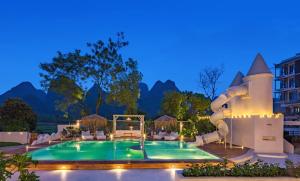 a pool at a resort with mountains in the background at Yangshuo OrangeWhite Resort - An Exclusive Cave - Inspired Haven by the River - Featuring Panoramic Mountain Views-Infinity Pool & Alpaca Encounters & Tailor-Made Excursions in Yangshuo