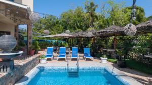 a swimming pool with blue chairs and an umbrella at Bijoutier Apartments in Grand'Anse Praslin