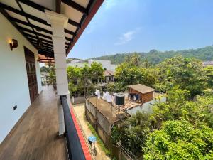 an outdoor balcony of a house with a view of trees at DK Korean Apartment in Unawatuna