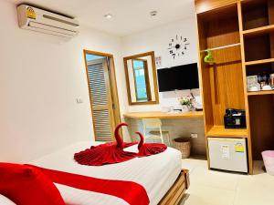a bedroom with a bed with red sheets and a desk at PJ Patong Resortel in Patong Beach