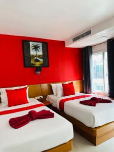 two beds in a red room with red walls at PJ Patong Resortel in Patong Beach