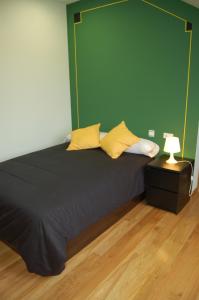 a bed with two yellow pillows and a green wall at Hostería El Laurel in Hoz de Anero