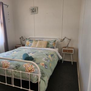 a bedroom with a bed with a floral bedspread at A Magic Shack - relax, recharge, frolic & fish in Tumby Bay +4 photos
