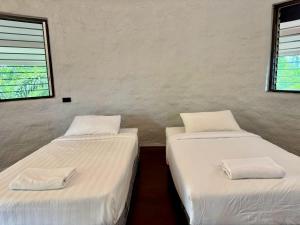 two twin beds in a room with a window at บ้านดิน 2 ชั้น in Khanong Phra