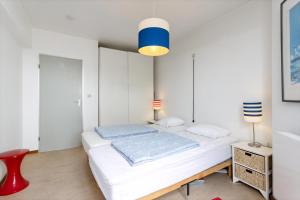 1 dormitorio blanco con 1 cama y 1 silla roja en Les Voiliers 21, en Sint-Idesbald