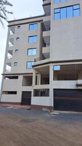 a large apartment building with a parking garage next to it at Delight stays in Ongata Rongai 