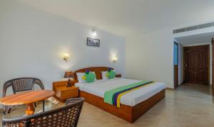 a bedroom with a bed and a table and chairs at Treebo Sadhoo Heritage in Kannur +25 photos