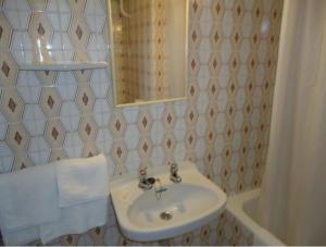 uma casa de banho com um lavatório, um espelho e uma banheira em Residència Restaurant Indalo em Andorra-a-Velha