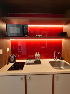 cocina con fregadero y pared roja en Mandala Coast Chambay Bình Thuận, en Ấp Nhơn Long