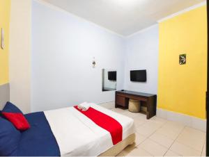 a bedroom with a bed and a desk in it at YUTAKA INN Sriwijaya Tegalsari Surabaya in Surabaya