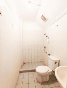 a bathroom with a toilet and a sink at YUTAKA INN Sriwijaya Tegalsari Surabaya in Surabaya +6 photos