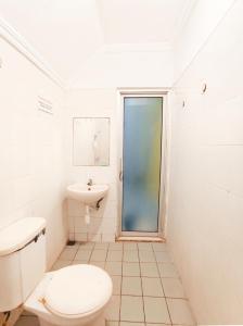 a white bathroom with a toilet and a sink at YUTAKA INN Sriwijaya Tegalsari Surabaya in Surabaya