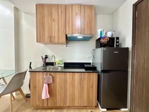 カガヤン・デ・オロにある25F Condo at The Loop Tower Limketkai Center CDOのキッチン(黒い冷蔵庫、木製キャビネット付) +4枚の写真