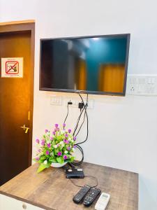 un jarrón de flores sentado en una mesa con TV en Hotel Pim-pri Stays,Pune, en Pune
