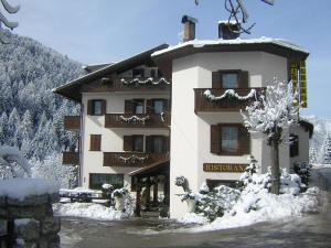 un grand bâtiment avec de la neige au sol dans l'établissement Albergo Miravalle, à Auronzo di Cadore