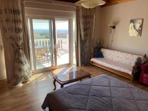 a living room with a bed and a couch and a balcony at Olympus View in Palaión Keramídion