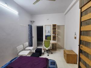 a bedroom with a bed and chairs and a desk at Anusattva Vatika in Bengaluru