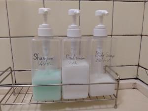 four bottles of soap on a shelf in a bathroom at Hostel 鶴々 in Shingū