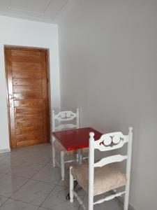 una sala da pranzo con un tavolo rosso e due sedie di Appartement Anne Djerba Phare a Al Maqārisah